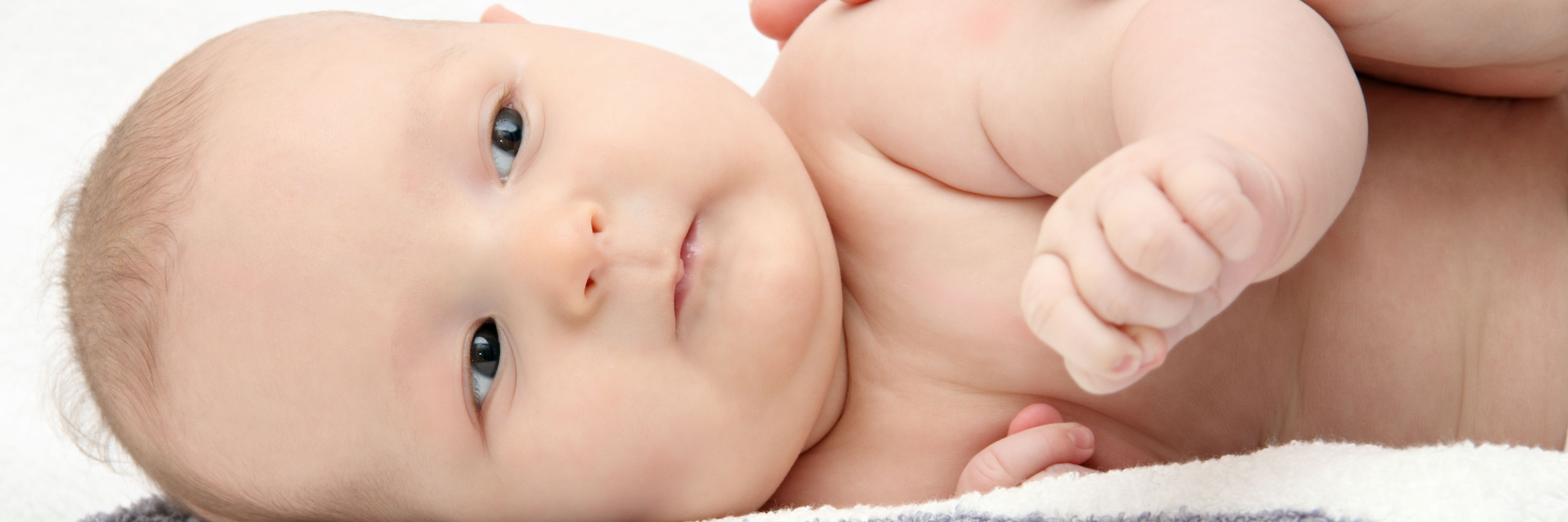 Baby der ligger på siden med en hånd hvilende på sig
