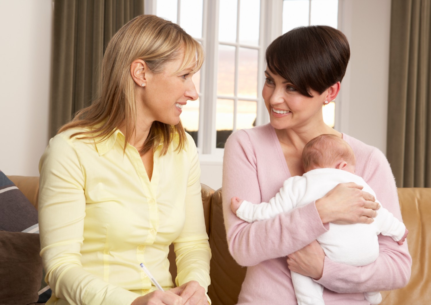 Sundhedsplejerske der taler med mor og barn